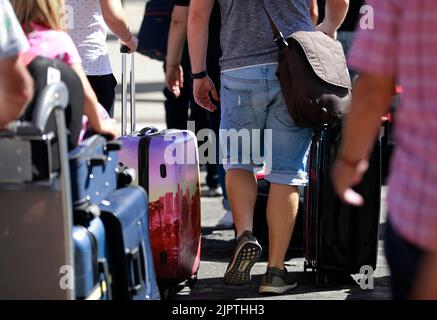 Palma, Spain. 20th Aug, 2022. People with suitcases stand at Palma de Mallorca airport. Credit: Clara Margais/dpa/Alamy Live News Stock Photo