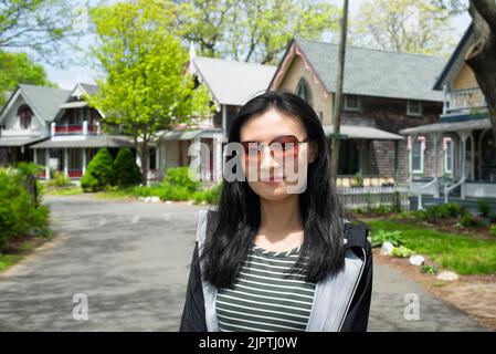 A chinese woman standing on a road through the national historic landmarks oak bluffs camp meeting association from the 19th century on martha's viney Stock Photo