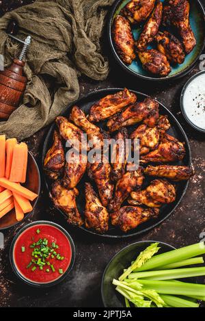 Grilled spicy chicken wings served with tomato and yogurt dips, celery and carrot Stock Photo