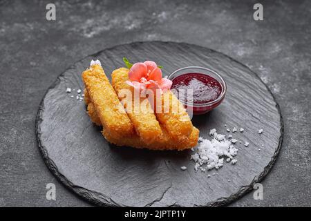 Cheese nuggets with sauce on a round stone, on a dark background Stock Photo