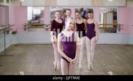 portrait of a young girl ballet dancer in a lilac ballet leotard, smiling, gracefully performing a ballet figure. High quality photo Stock Photo
