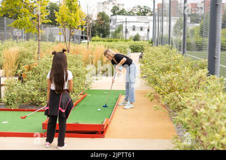 Miniature golf outdoor. Little caucasian girl golfing in the mini golf course. Stock Photo