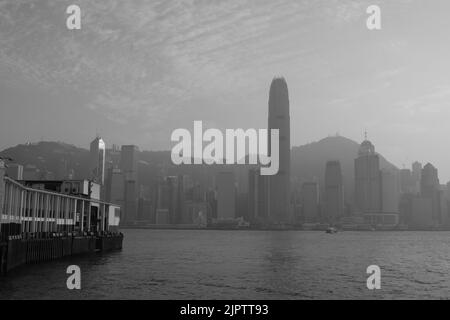 Star Ferry Pier at Tsim Sha Tsui Hong Kong Black White Photo Coloured Star Ferry Green White Ferry Background is Central of Hong Kong Island IFC Stock Photo