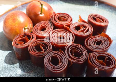 Natural and healthy snack food - fruit pastille from plums on a blue plate. Pastille fruit rolls.  Fruit Marshmallow. Homemade plum marshmallow. Stock Photo
