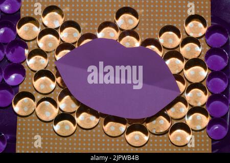 Abstract orange background with dots and purple paper lips as copy space and beads that reflect colors differently on both sides purple part, summer a Stock Photo
