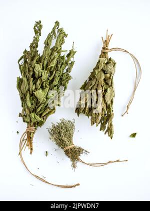 Bundles of dried mint and thyme leaves on white background. Overhead shot. Stock Photo