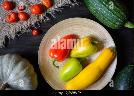 Vegetable marrow and sweet pepper on wood table, flat lay. Top view of fresh zucchini, pumpkin and tomatoes in kitchen, set of organic food. Concept o Stock Photo