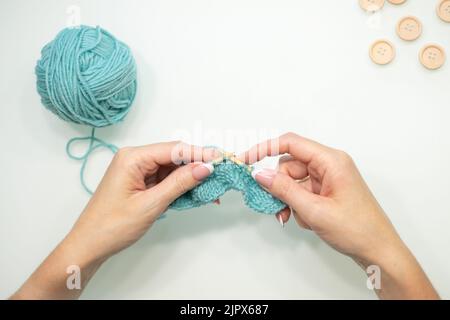 Women's hands knit on a white background. Knitting on knitting needles from wool and cotton. handmade. Stock Photo
