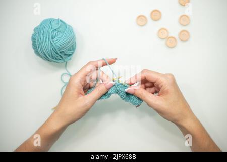 Women's hands knit on a white background. Knitting on knitting needles from wool and cotton. handmade. Stock Photo
