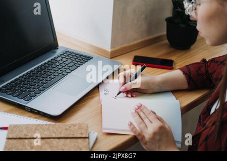 Taskmanager, To do List, Boosts Productivity, Close up of female hands and paper to do list in notepad Stock Photo