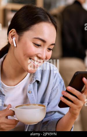 Happy young Asian woman student using smartphone watching videos. Stock Photo