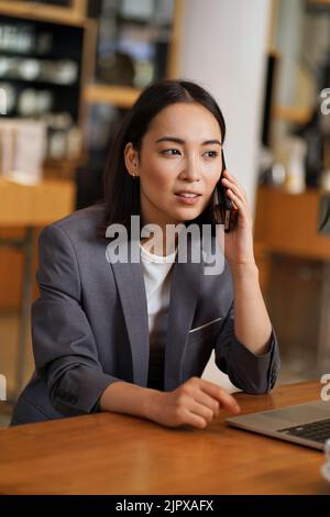 Busy Asian young business woman manager talking on phone making call. Stock Photo