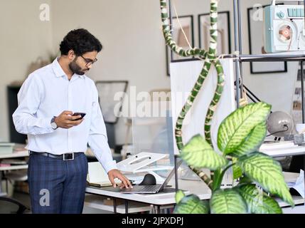 Busy indian business man working standing in modern office space at work. Stock Photo