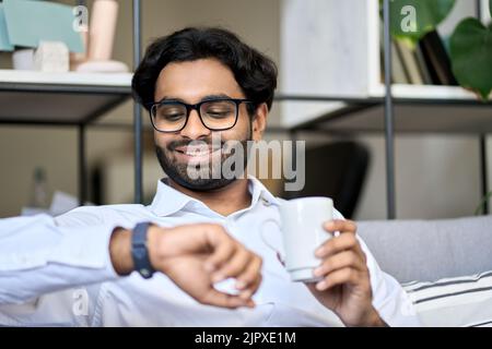 Smiling indian business man drinking coffee in morning checking time. Stock Photo