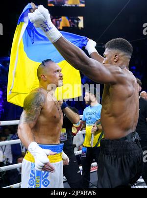 Anthony Joshua (right) holds up a Ukrainian flag as he speaks to Oleksandr Usyk at the end of their World Heavyweight Championship WBA Super IBF, IBO and WBO fight at the King Abdullah Sport City Stadium in Jeddah, Saudi Arabia. Picture date: Saturday August 20, 2022. Stock Photo