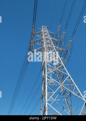 Low angle view of an electricity transmission pylon against blue sky Stock Photo