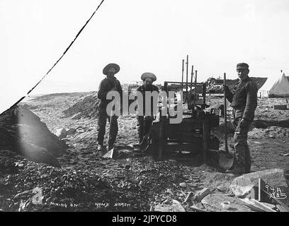 Three men mining for gold on Nome Beach, Alaska, ca 1900 Stock Photo