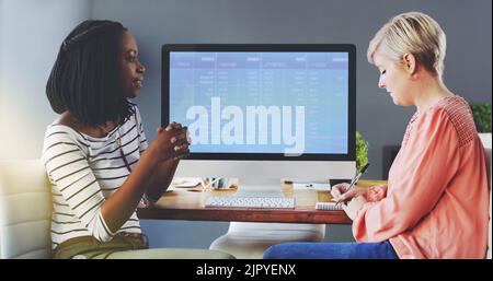 Putting their heads together for a quick brainstorming session. two businesswomen brainstorming together in an office. Stock Photo
