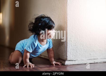 Some hide and go seek. a little baby boy playing and hiding around a corner at home during the day. Stock Photo