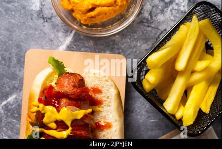 A tasty hotdog with french fries and cheese sauce Stock Photo