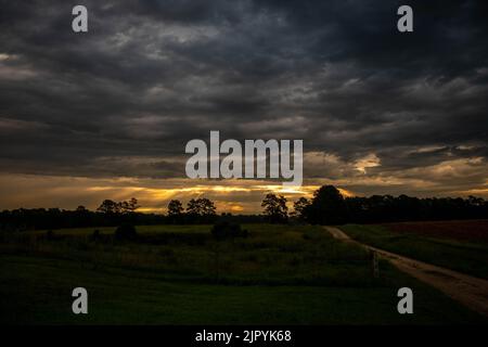 Dramatic clouds stifle the early morning shunshine as the remaining rays of light pierce through to the land. Raleigh, North Carolina. Stock Photo