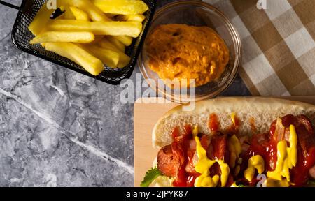A tasty hotdog with french fries and cheese sauce Stock Photo