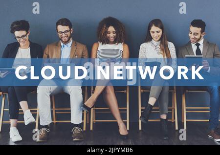Connected on the cloud. Studio shot of businesspeople using wireless technology with the words cloud network superimposed over them against a gray Stock Photo
