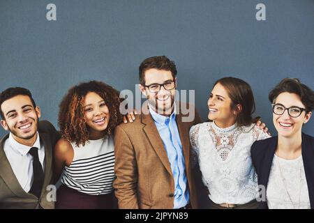 Its great having a team who support you. Studio portrait of a group of businesspeople standing together against a gray background. Stock Photo