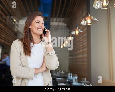 Customers keep calling to leave compliments about her business. a young entrepreneur talking on a cellphone in a cafe. Stock Photo