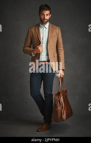 Stylish and strong. Studio shot of a handsome young man posing against a gray background. Stock Photo
