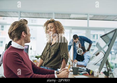 An open working environment makes for open and friendly conversation. two young colleagues having a friendly chat in a modern office. Stock Photo