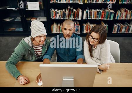 Studying together. High angle shot of three young university students studying in the library. Stock Photo