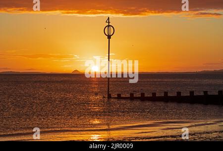 Portobello, Edinburgh, Scotland, UK. 21st August 2022. Cool colourful sunrise with temperature of 12 degrees centigrade, feeling autumnal at dawn for the quiet seaside by the Firth of Forth. Pictured sunrise looking over waterof the Firth of Forh towards Berwick Law in East Lothian. Credit: Arch White/alamy live news. Stock Photo