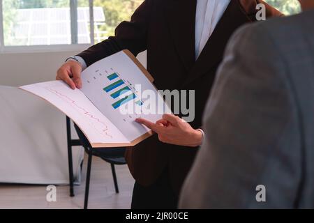 Two unrecognizable men in suits analyzing performance charts of a business. Business man presenting his performance. Data analyst presenting his performance to his boss. High quality photo Stock Photo