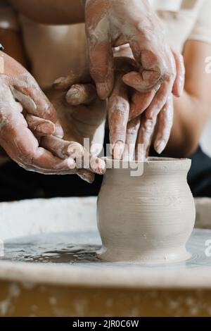 Hands close-up at pottery workshop learning to make clay bowl. People doing handmade dishes. Lesson for adults at ceramics studio Stock Photo
