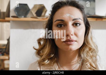 Close-up dirty woman potter portrait, self-employed pottery artist in creative studio working with raw clay Cheerful ceramics art teacher in workshop Stock Photo