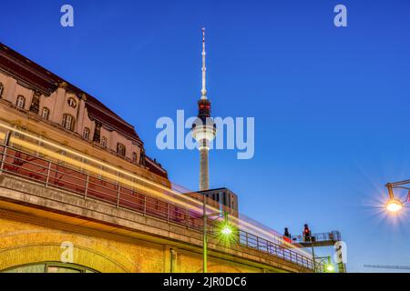 The iconic TV Tower in Berlin at dusk with a motion blurred commuter train Stock Photo