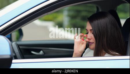 Mature woman feels sick sneezing in car black leather cabin Stock Photo