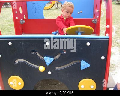 my two year old son driving a wooden car in the playground Stock Photo