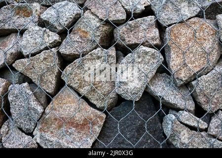 Gabion wall closeup. Textured background. Gabion is stones in wire mesh used for erosion control and slope reinforcement Stock Photo