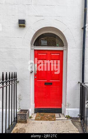 A white painted house with a  red front door with a fanlight window arch above it in Fitzrovia, London W1 Stock Photo