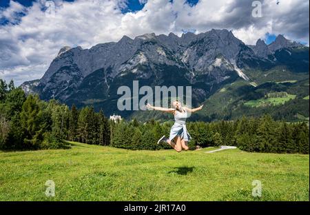 Girl jumping in the air at the meadow on the Sound of Music trail near Werfen, Austria Stock Photo