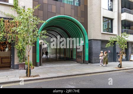 People walking past the turquoise green ceramic tunnel on  Rathbone Square , Fitzrovia, London W1 Stock Photo