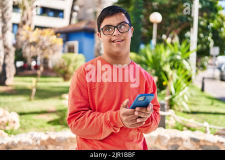 Down syndrome man smiling confident using smartphone at park Stock Photo
