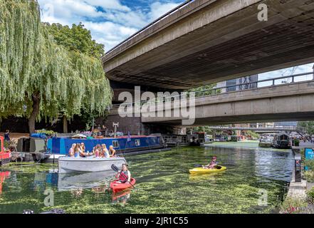 People in kayaks and a group of girl in a boat passing under the Westway on the Paddington arm of the Grand Union Canal , Paddington ,London, W2 Stock Photo