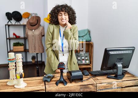 Young middle eastern woman working as manager at retail boutique touching mouth with hand with painful expression because of toothache or dental illne Stock Photo