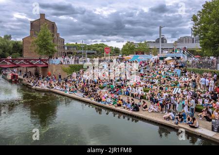 Crowds of people sitting on the canalside steps on the Regent's canal near Granary Square at Kings Cross on a warm summers evening , London Stock Photo