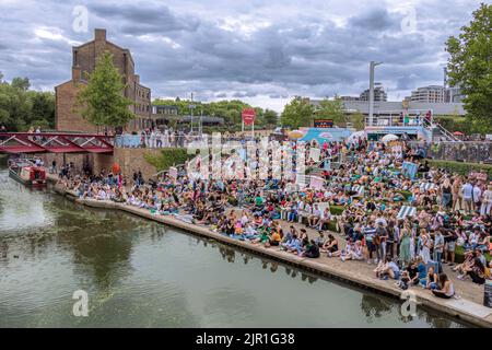 Crowds of people sitting on the canalside steps on the Regent's canal near Granary Square at Kings Cross on a warm summers evening , London Stock Photo