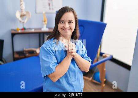 Down syndrome woman wearing physiotherapy uniform standing at physiotherapist clinic Stock Photo