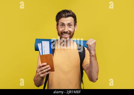 Finally vacation. Excited middle aged man with suitcase, passport and tickets exclaiming happiness, yellow background Stock Photo